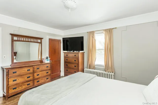 a bedroom with a bed and a flat tv screen on dresser