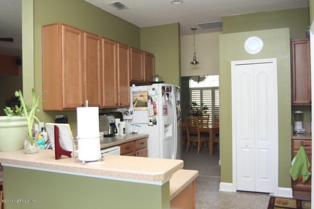 97178 Castle Ridge Drive Yulee, FL 32097 - Photo 7 of 14 a kitchen with stainless steel appliances kitchen island granite countertop a refrigerator and a sink