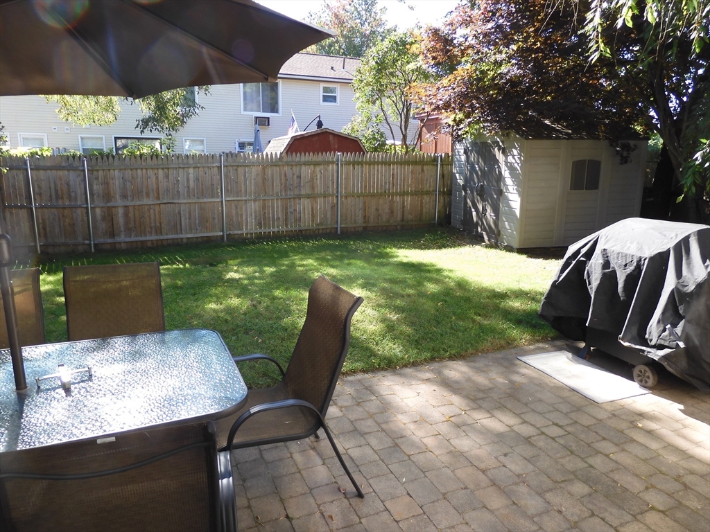 134 Old Ferry Road, Unit A Haverhill, MA 01830 - Photo 19 of 24 a view of a backyard with table and chairs potted plants and a palm tree