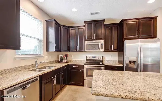 a kitchen with stainless steel appliances granite countertop a stove a sink and a refrigerator
