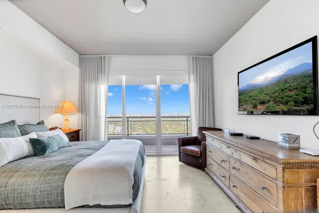 a bedroom with a large bed and a flat tv screen on dresser