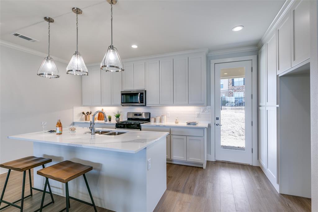 635 Community Lane Rockwall, TX 75087 - Photo 13 of 25 a kitchen with kitchen island granite countertop a stove a sink a center island a dining table and chairs
