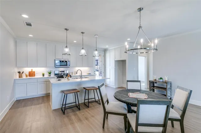 a kitchen with a dining table chairs and wooden floor
