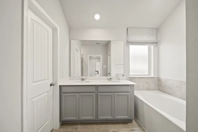 a bathroom with a double vanity sink a mirror and a bathtub