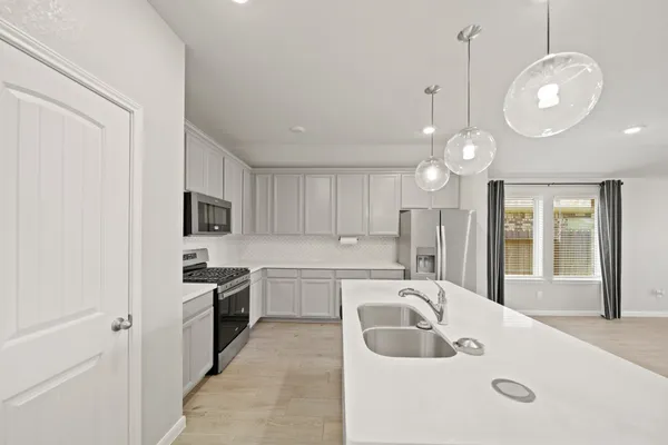 a large white kitchen with a sink stainless steel appliances and cabinets