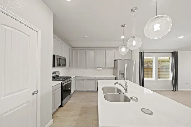 a large white kitchen with a sink stainless steel appliances and cabinets