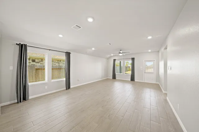 a view of an empty room with glass door and windows
