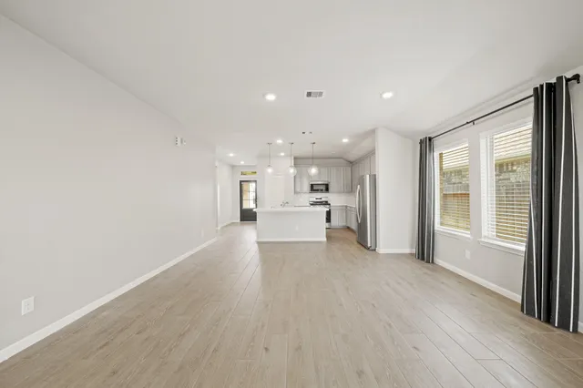 a view of a big room with wooden floor and windows
