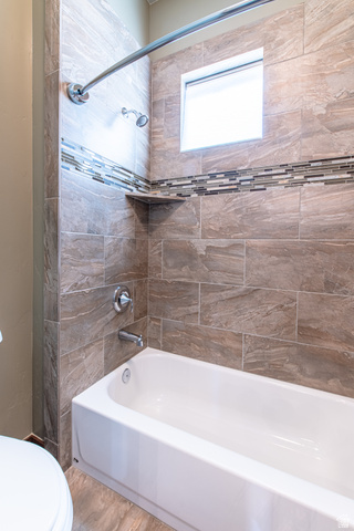 322 340 E Street Ivins, UT 84738 - Photo 41 of 61 Bathtub and shower combination featuring neutral-toned tile surround, decorative mosaic tile accent band, built-in shower niche, and a privacy window