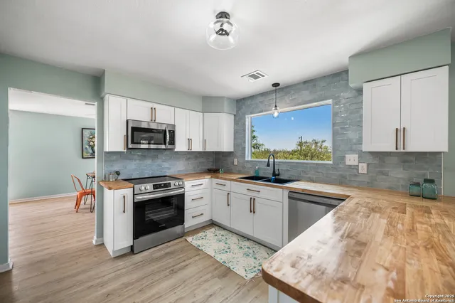 a kitchen with stainless steel appliances granite countertop a stove top oven a sink and white cabinets
