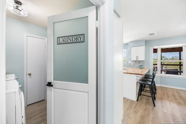 a view of a hallway with wooden floor and a bathroom