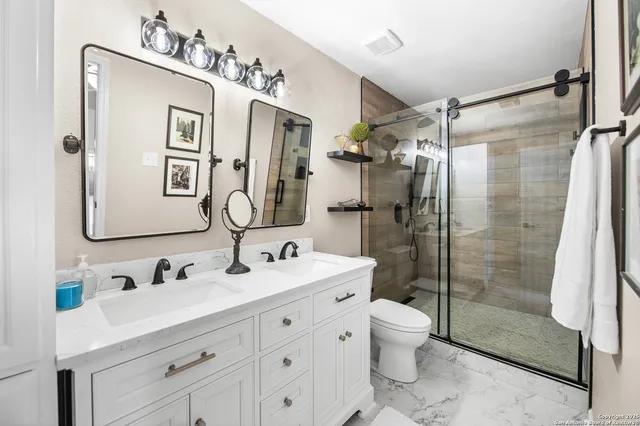 a bathroom with a double vanity sink toilet mirror and shower