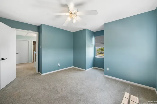 an empty room with a chandelier fan and windows
