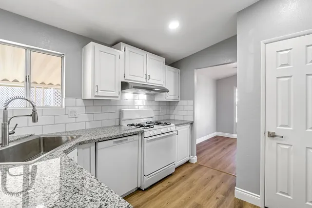 a kitchen with stainless steel appliances granite countertop a sink a stove and a refrigerator