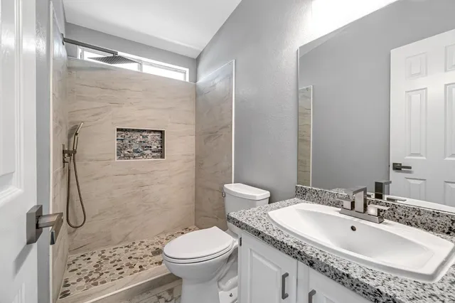 a bathroom with a granite countertop sink toilet and shower