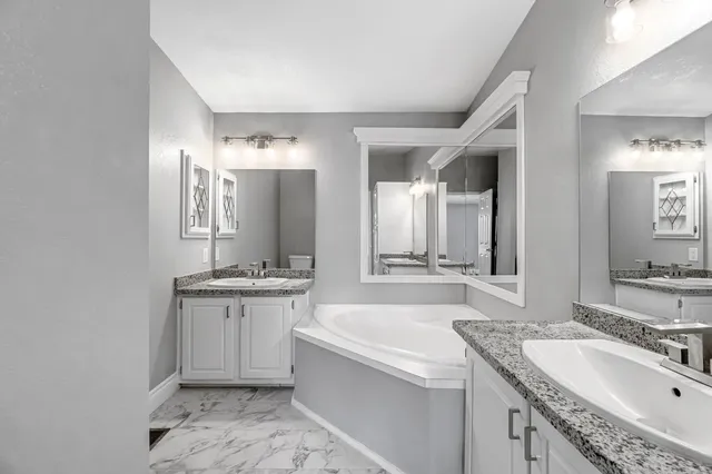 a bathroom with a granite countertop bathtub sink double and mirror