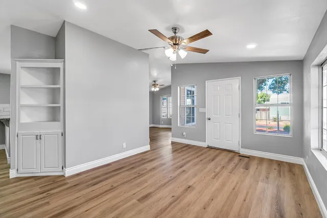 a view of an empty room with wooden floor and a window