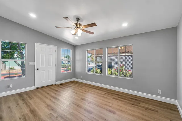 a view of an empty room with a window and wooden floor