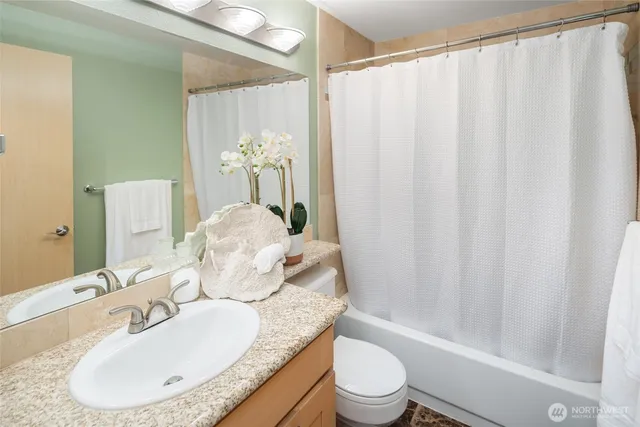 a bathroom with a granite countertop sink a toilet and shower
