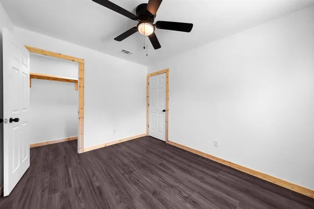 an empty room with wooden floor a ceiling fan and closet