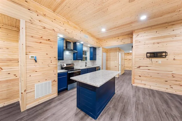 a kitchen with stainless steel appliances kitchen island wooden floors granite counter tops and a window