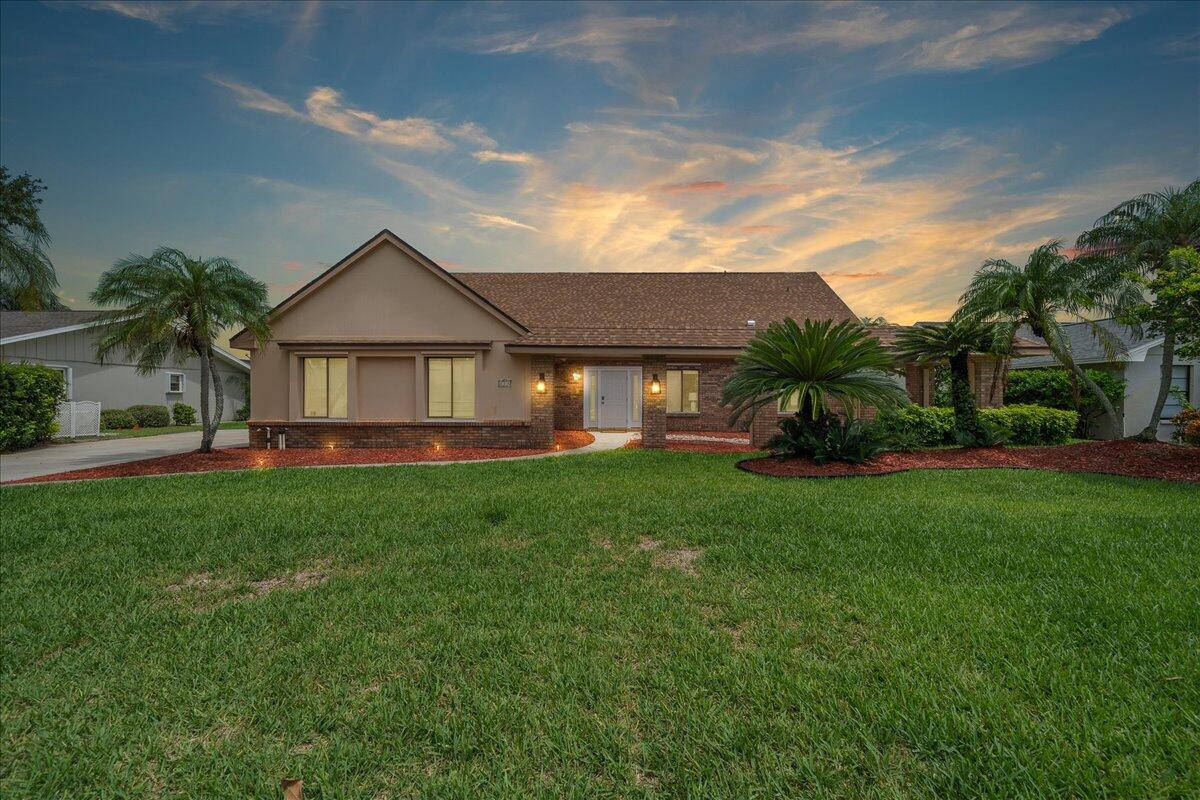 a front view of a house with a yard and palm trees