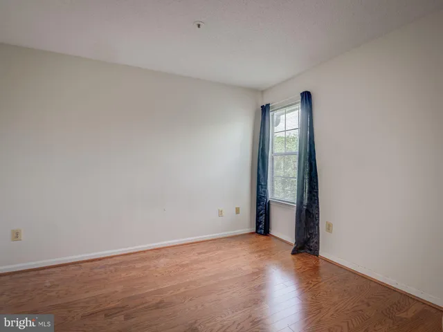 an empty room with wooden floor and window
