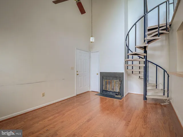 an empty room with wooden floor fireplace and windows