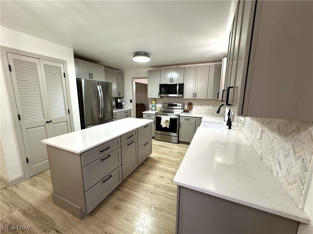 8359 Gibson Road Canfield, OH 44406 - Photo 6 of 27 Kitchen featuring gray cabinetry, backsplash, appliances with stainless steel finishes, and light wood finished floors