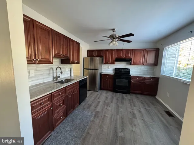 a kitchen with granite countertop a sink a counter top space appliances and cabinets