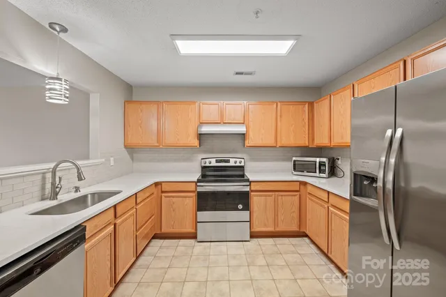 a kitchen with stainless steel appliances granite countertop a sink stove refrigerator and cabinets