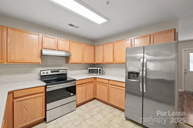 a kitchen with cabinets stainless steel appliances and a window