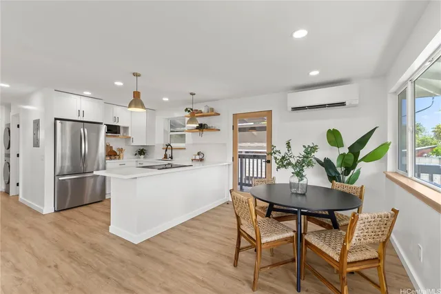 a kitchen with stainless steel appliances a dining table chairs wooden floor and a refrigerator