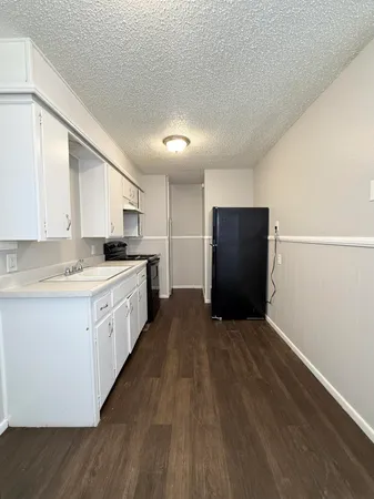 a kitchen with granite countertop white cabinets and refrigerator