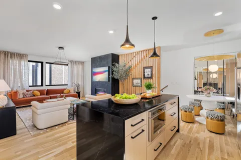 a room with stainless steel appliances kitchen island granite countertop wooden floor a large window and a view of living room