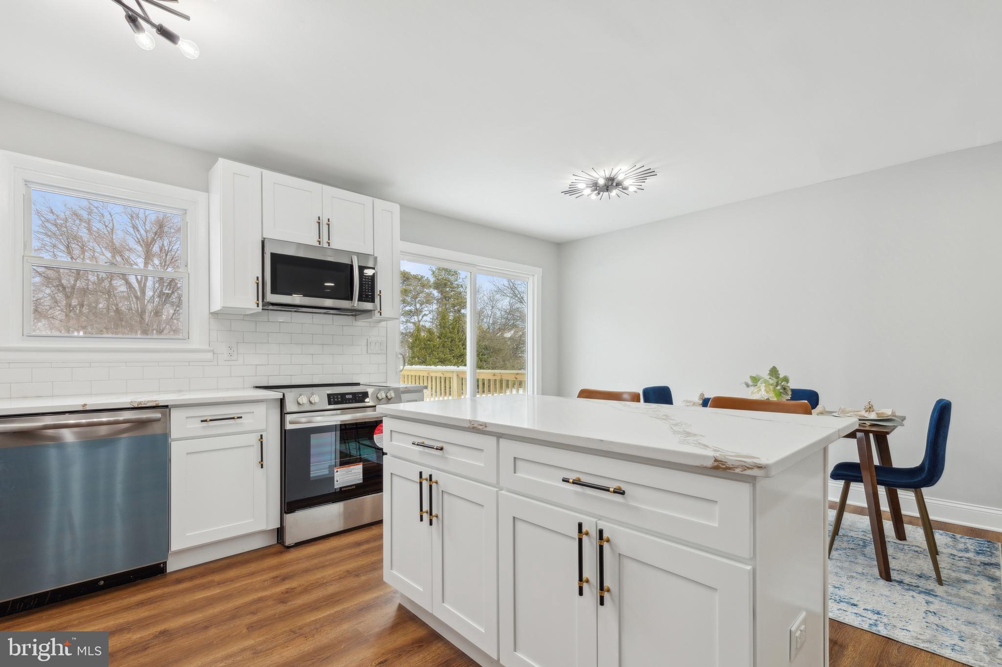 7760 Telegraph Road Severn, MD 21144 - Photo 16 of 49 a kitchen with stainless steel appliances white cabinets a sink a stove a dining table and chairs