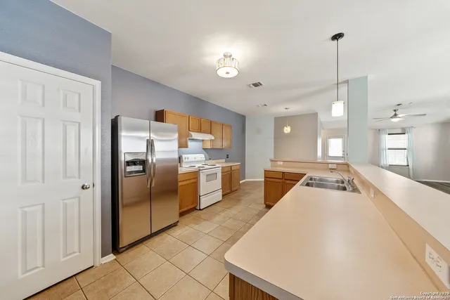 a kitchen with stainless steel appliances granite countertop a refrigerator a sink dishwasher and a stove with wooden floor