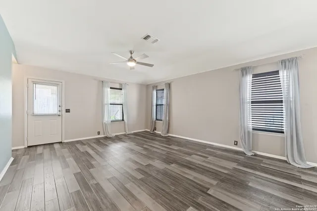 a view of an empty room with wooden floor and a window