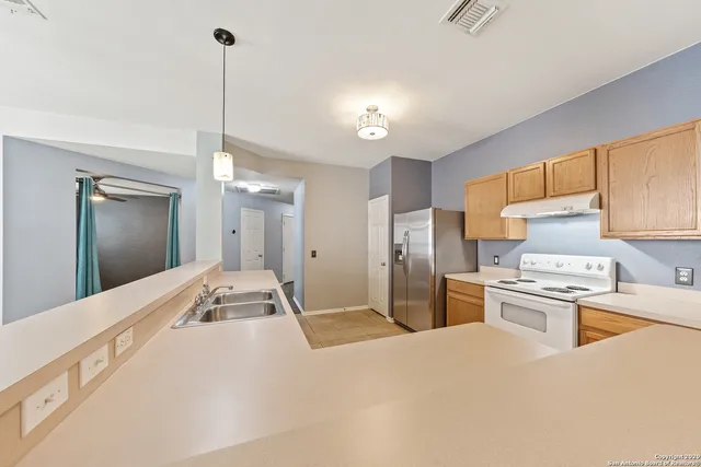 a kitchen with stainless steel appliances kitchen island granite countertop a sink a stove and refrigerator