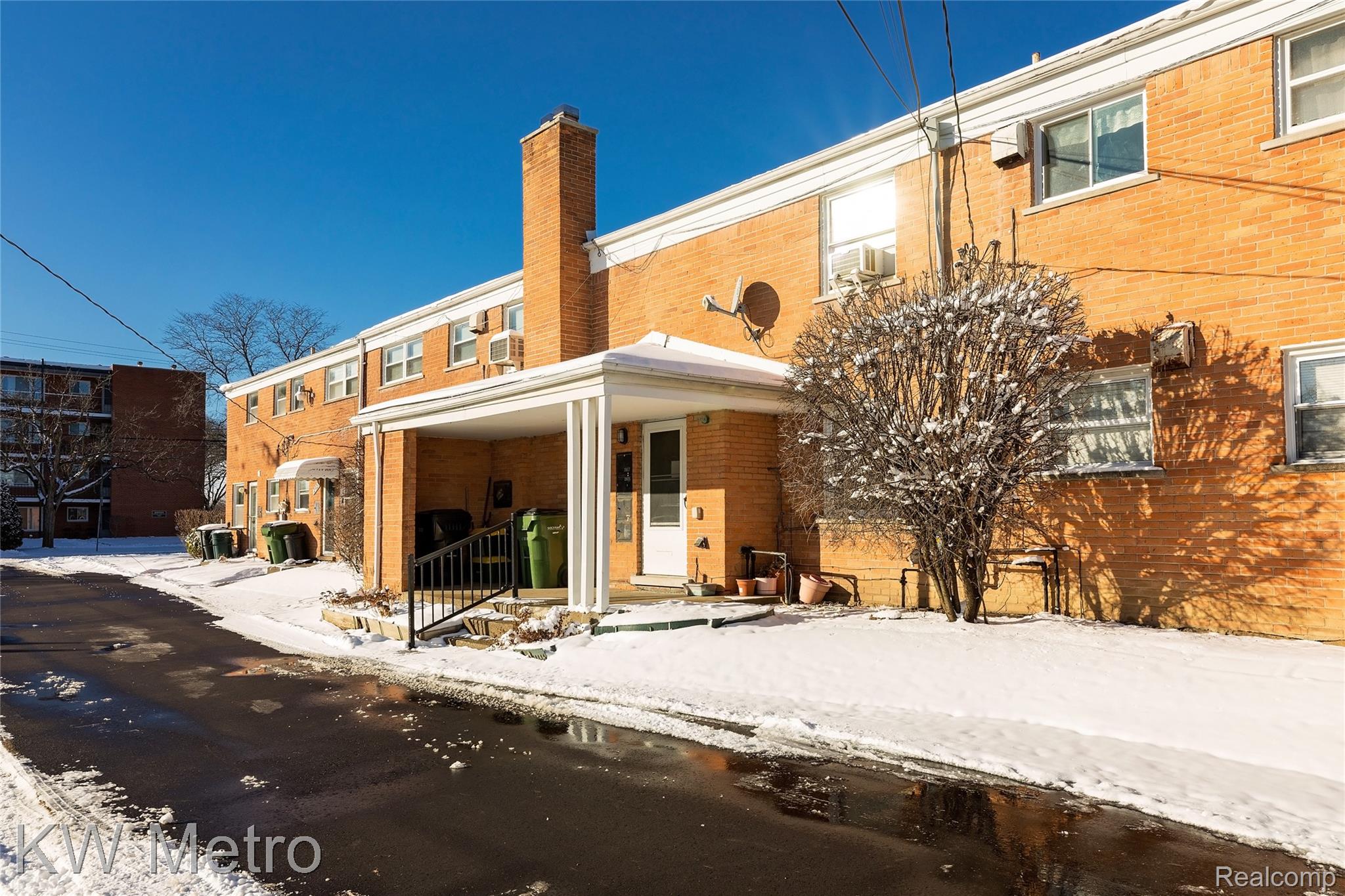 2817 West 13 Mile Road Royal Oak, MI 48073 - Photo 20 of 21 Snow covered rear of property with a chimney, brick siding, and cooling unit