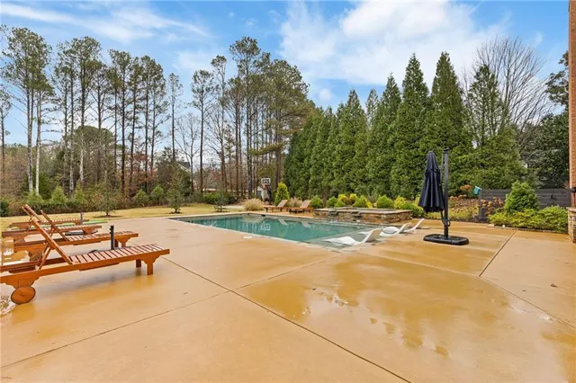 a large pool with lawn chairs and trees around