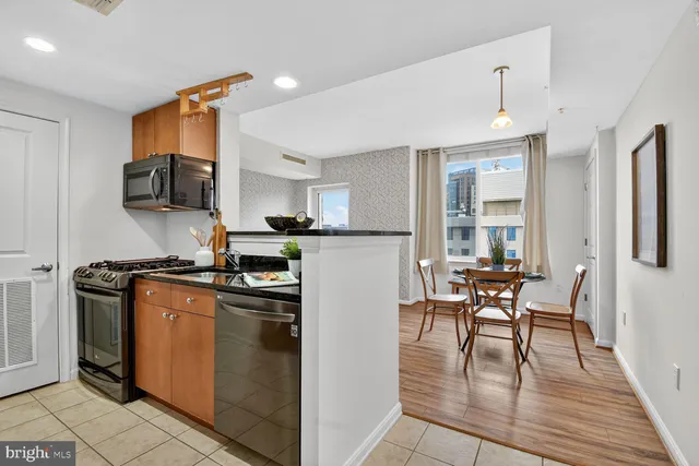 a kitchen with stainless steel appliances granite countertop a stove top oven a sink a dining table and chairs with wooden floor