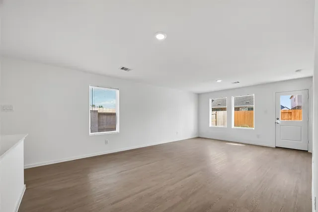 a view of an empty room with a window and wooden floor