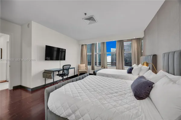 a bedroom with bed tv and a large window