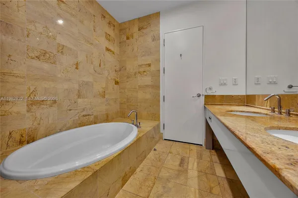 a bathroom with a granite countertop sink and a tub