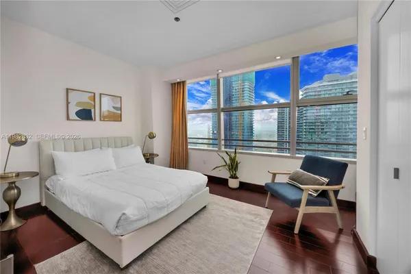 a bedroom with a bed a chair and a large window