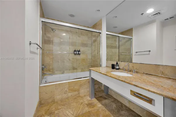 a bathroom with a granite countertop sink mirror and a bath tub