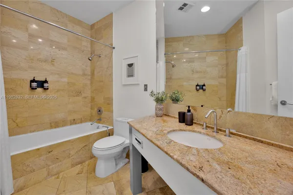 a bathroom with a granite countertop sink a toilet and shower