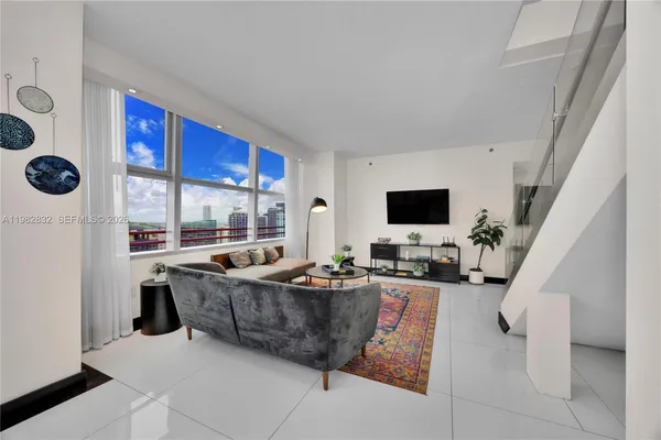 a living room with furniture a flat screen tv and a floor to ceiling window