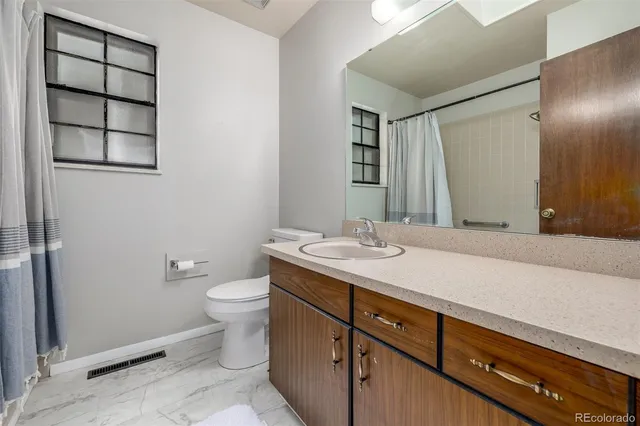 a bathroom with a granite countertop sink toilet and mirror